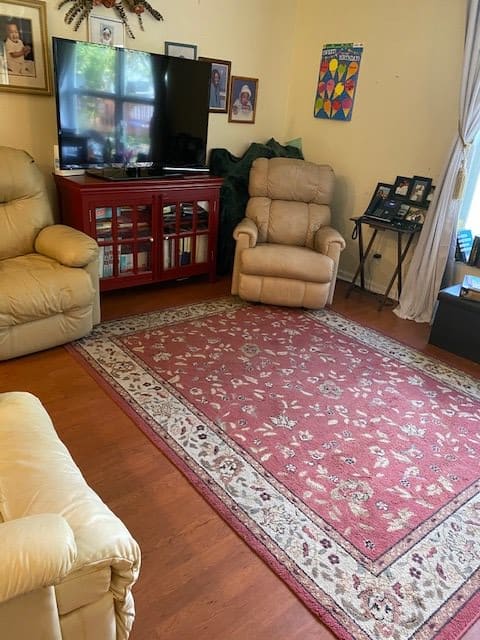 A cozy living room with beige sofas, a patterned rug, and a television.
