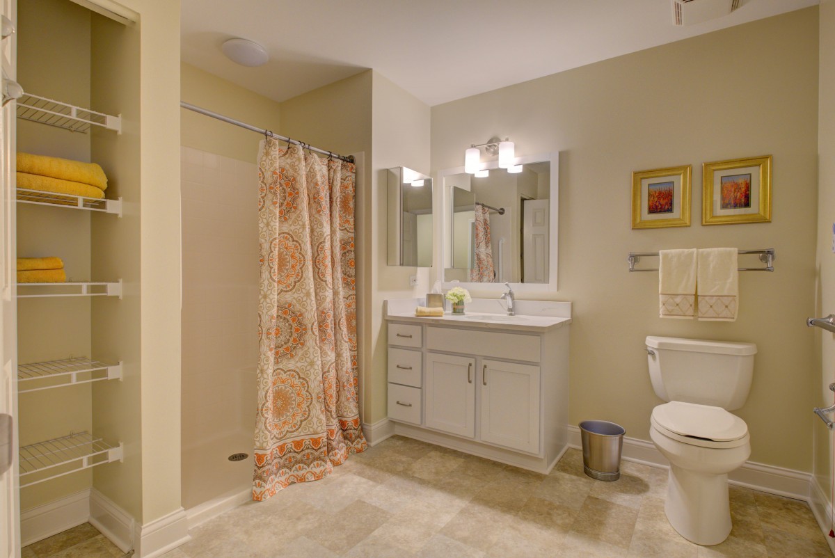 A well-lit bathroom featuring a vanity with a mirror, a shower area with a patterned curtain, and essential fixtures.