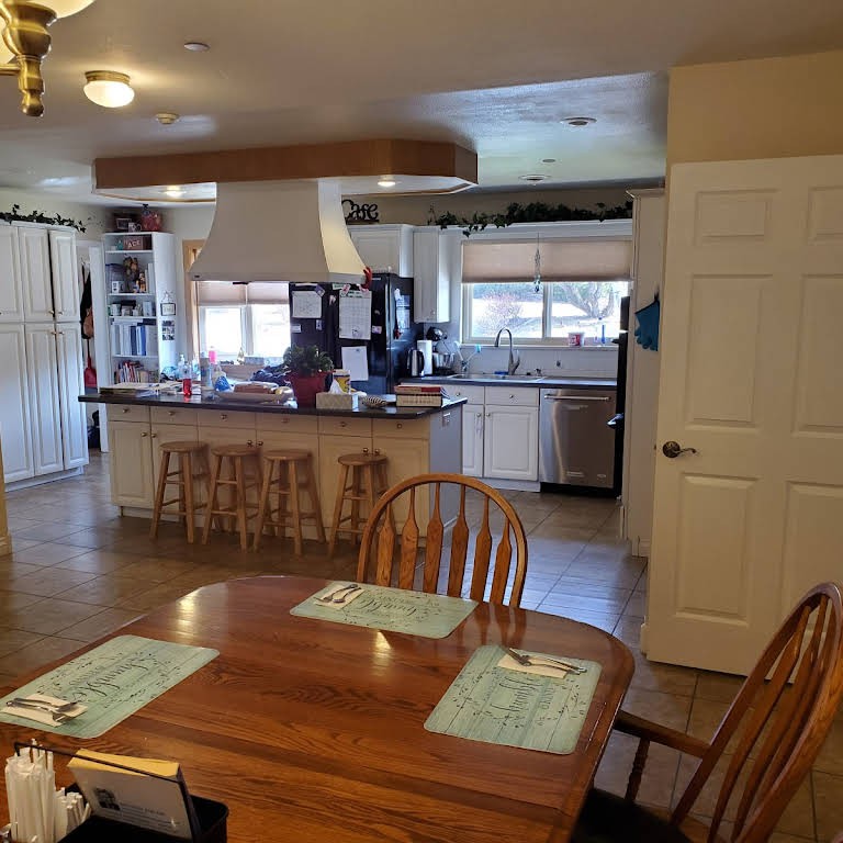 A spacious kitchen and dining area featuring a wooden table, chairs, and a counter with stools.