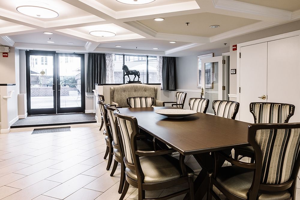 An elegant dining room with a long table and chairs, featuring ceiling lights and tasteful decor.