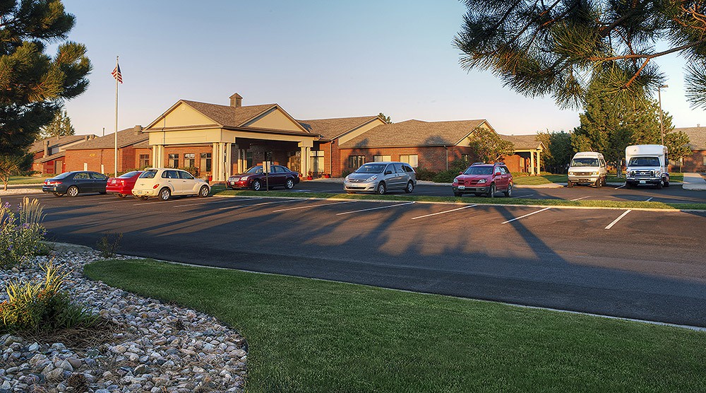 A view of a residential building with cars parked in the lot during sunset.