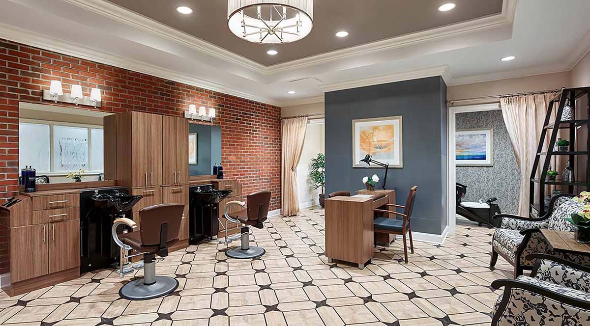 A stylish and modern salon interior with chairs, a brick accent wall, and elegant lighting.