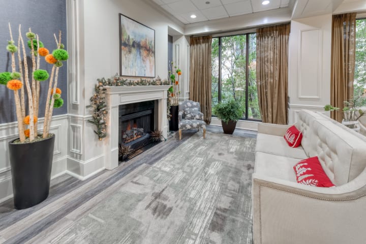 A modern living room with a fireplace, large windows, and stylish decor.
