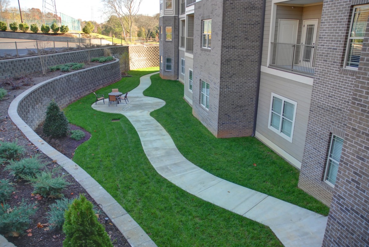 A landscaped area with a winding walkway beside an apartment building.