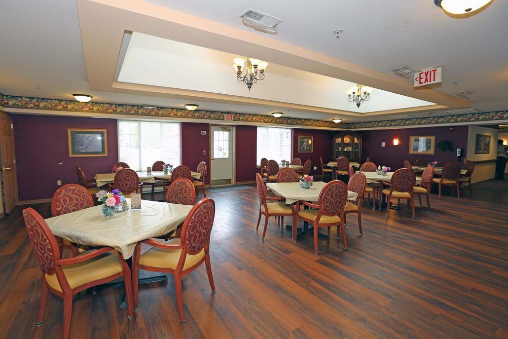 A spacious dining area with tables and chairs, featuring a wooden floor and chandeliers.