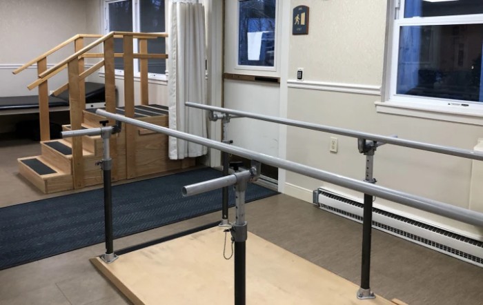 A physical therapy room featuring parallel bars used for rehabilitation exercises.