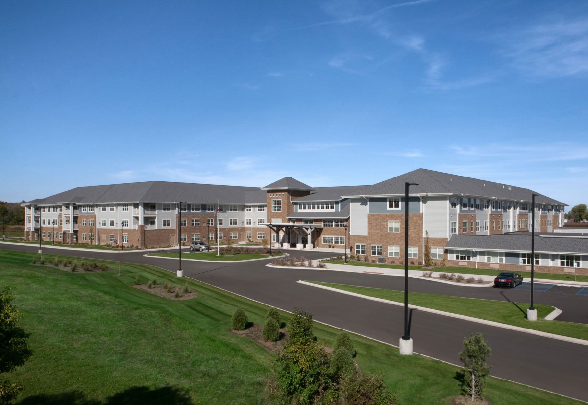 A modern school building with a spacious parking lot and surrounding greenery.