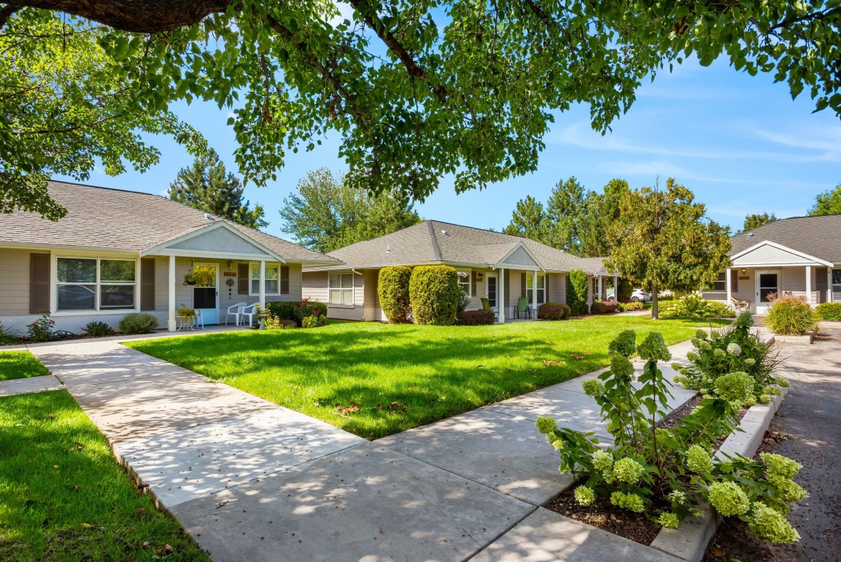 A serene residential neighborhood with well-maintained lawns and pathways under a clear blue sky.