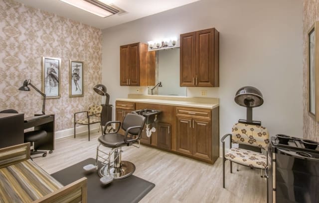 A cozy salon interior featuring a hairdressing station with a chair, mirror, and cabinetry.