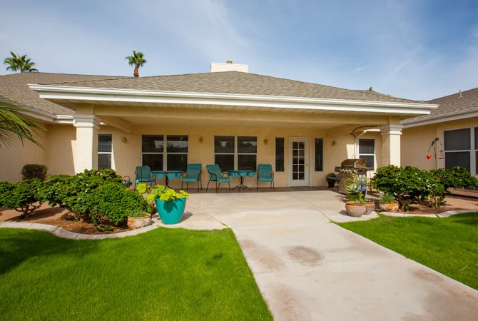 A view of a house with a spacious backyard and a well-maintained patio.