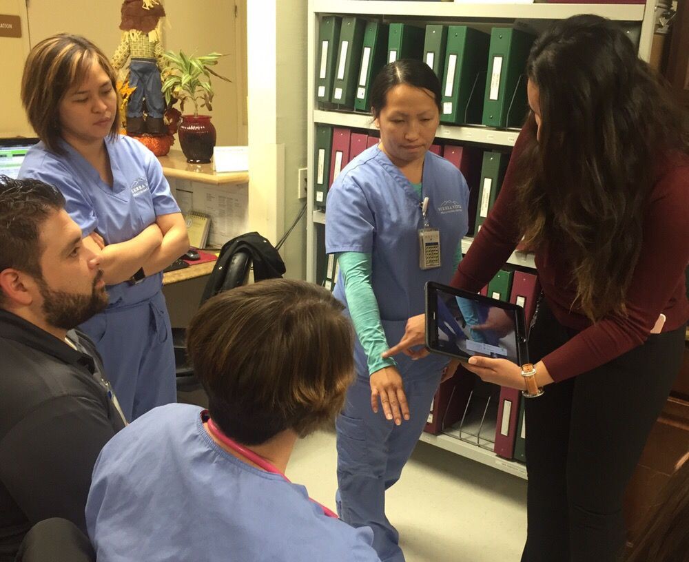 A medical team engaged in a discussion, with one member demonstrating something to the others.