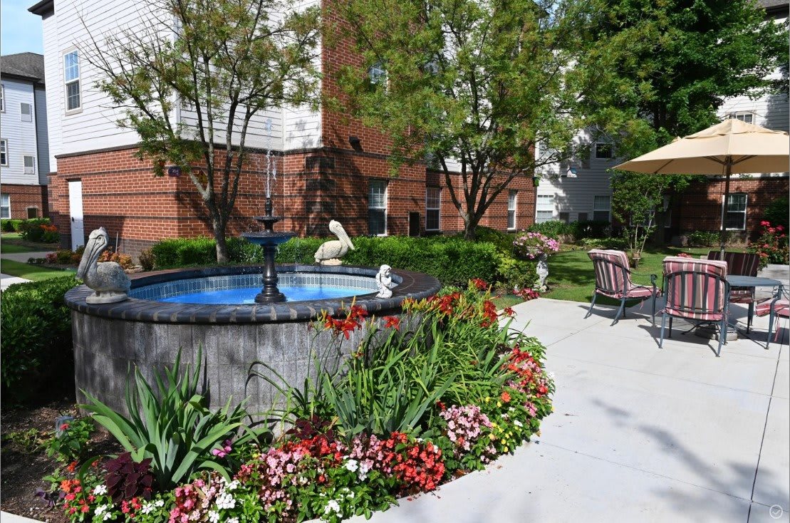 A peaceful garden with a fountain surrounded by vibrant flowers and lush greenery.