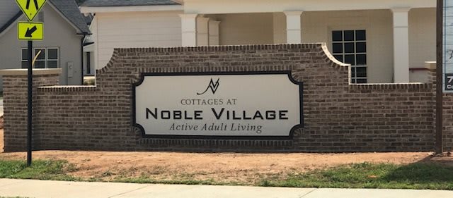 Entrance sign for Cottages at Noble Village, an active adult living community.