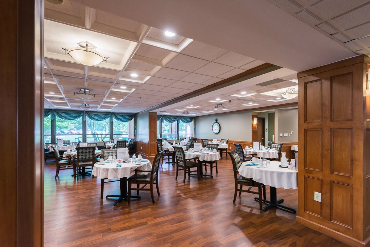 An elegant restaurant dining room with neatly arranged tables and chairs on a wooden floor.