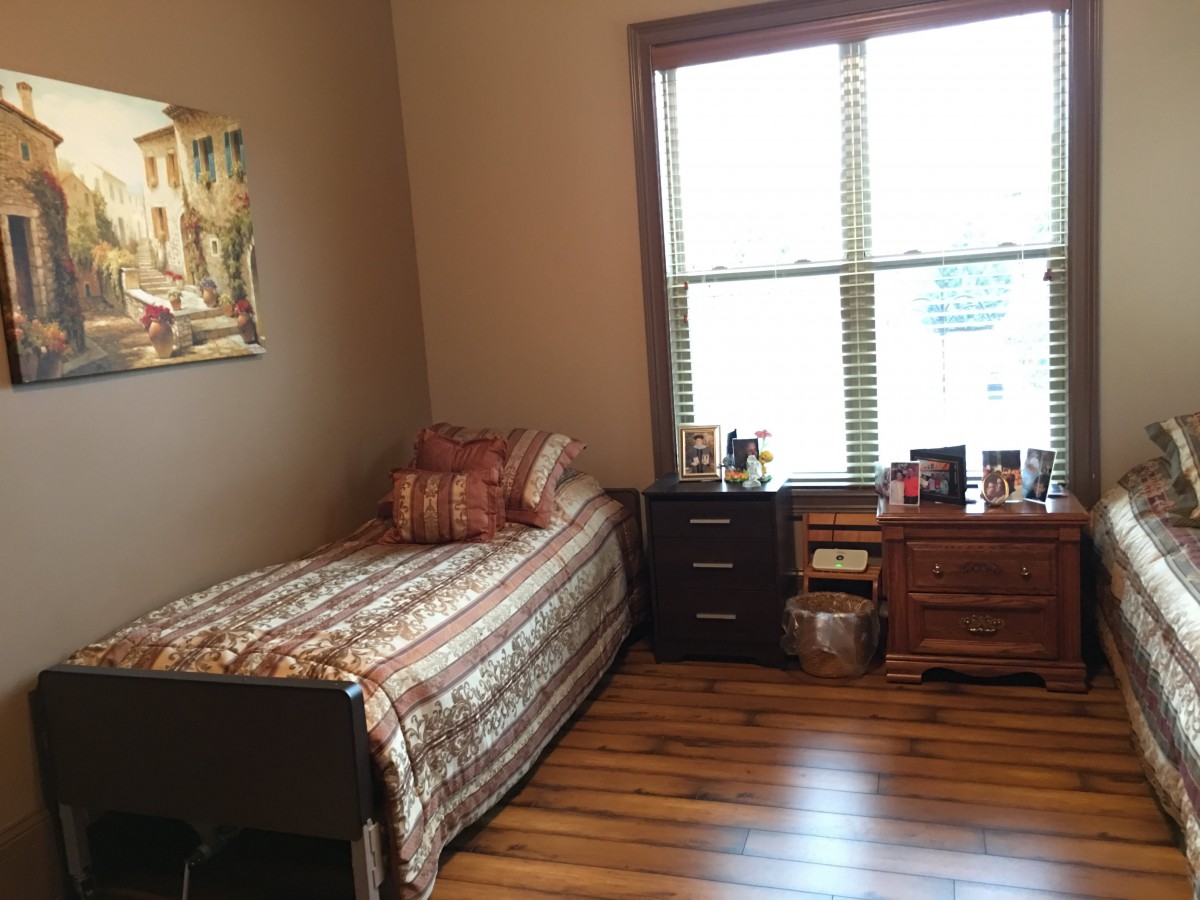 A tidy bedroom with a single bed, nightstand, and a window providing natural light.
