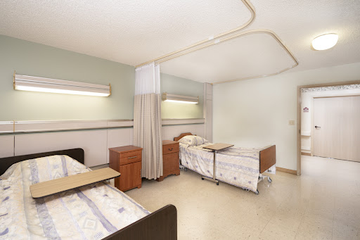 A view of a hospital patient room featuring two beds and a clean, calm environment.