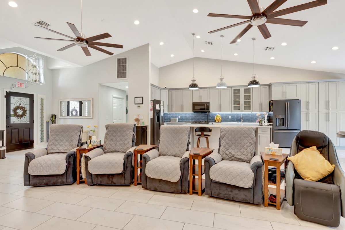 A spacious living area with multiple recliner chairs and a modern kitchen in the background.