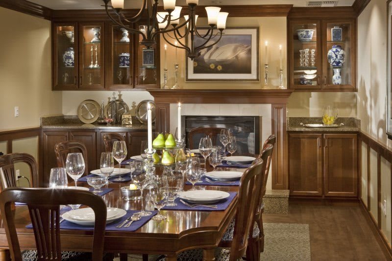 An elegantly set dining room table with a chandelier and wood furnishings.