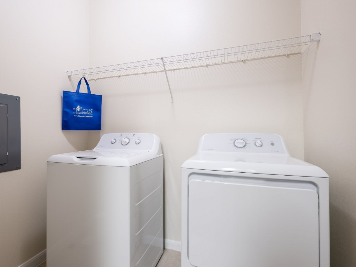 A laundry room featuring a washing machine and dryer with a hanging blue bag.