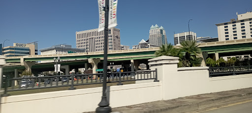 A bustling urban landscape featuring modern buildings and a highway under a clear blue sky.