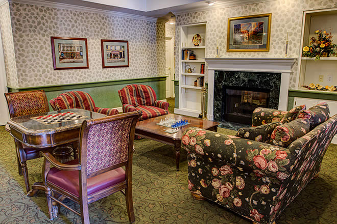 A cozy living room with a fireplace, featuring patterned furniture and wall art.