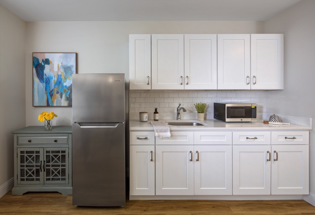 Modern kitchen with stainless steel fridge and white cabinets.