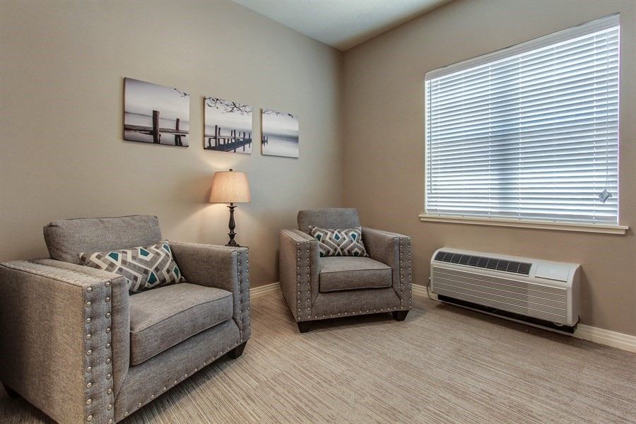 A cozy living room with two gray armchairs, a lamp, and wall art.