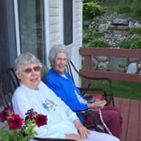 Two elderly women enjoying a relaxing time on the porch in rocking chairs.