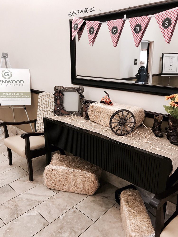 A decorated lobby with vintage elements, including hay bales and a wagon wheel, beneath a large mirror and patriotic flags.