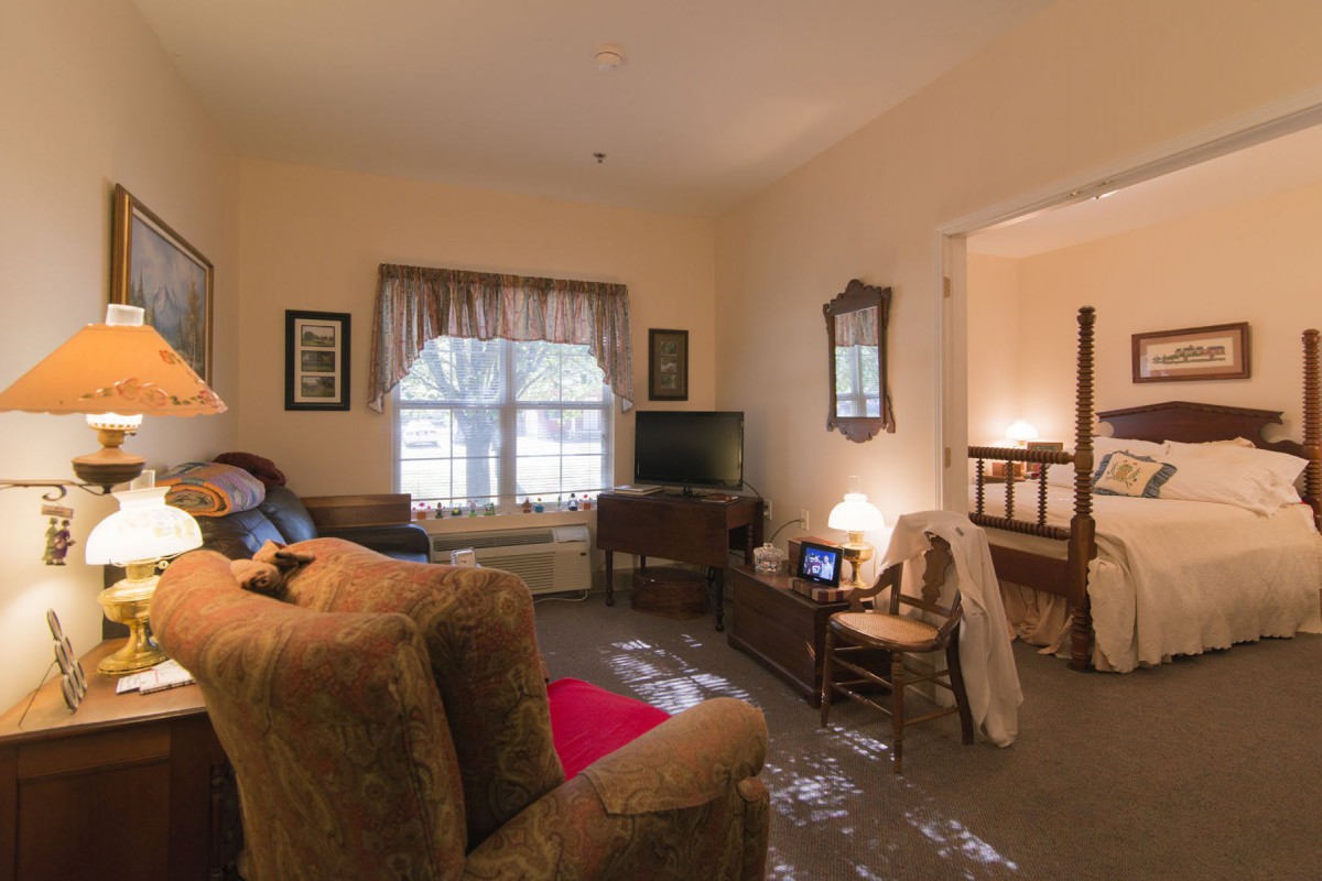 A cozy living room with a sofa, television, and window with curtains.