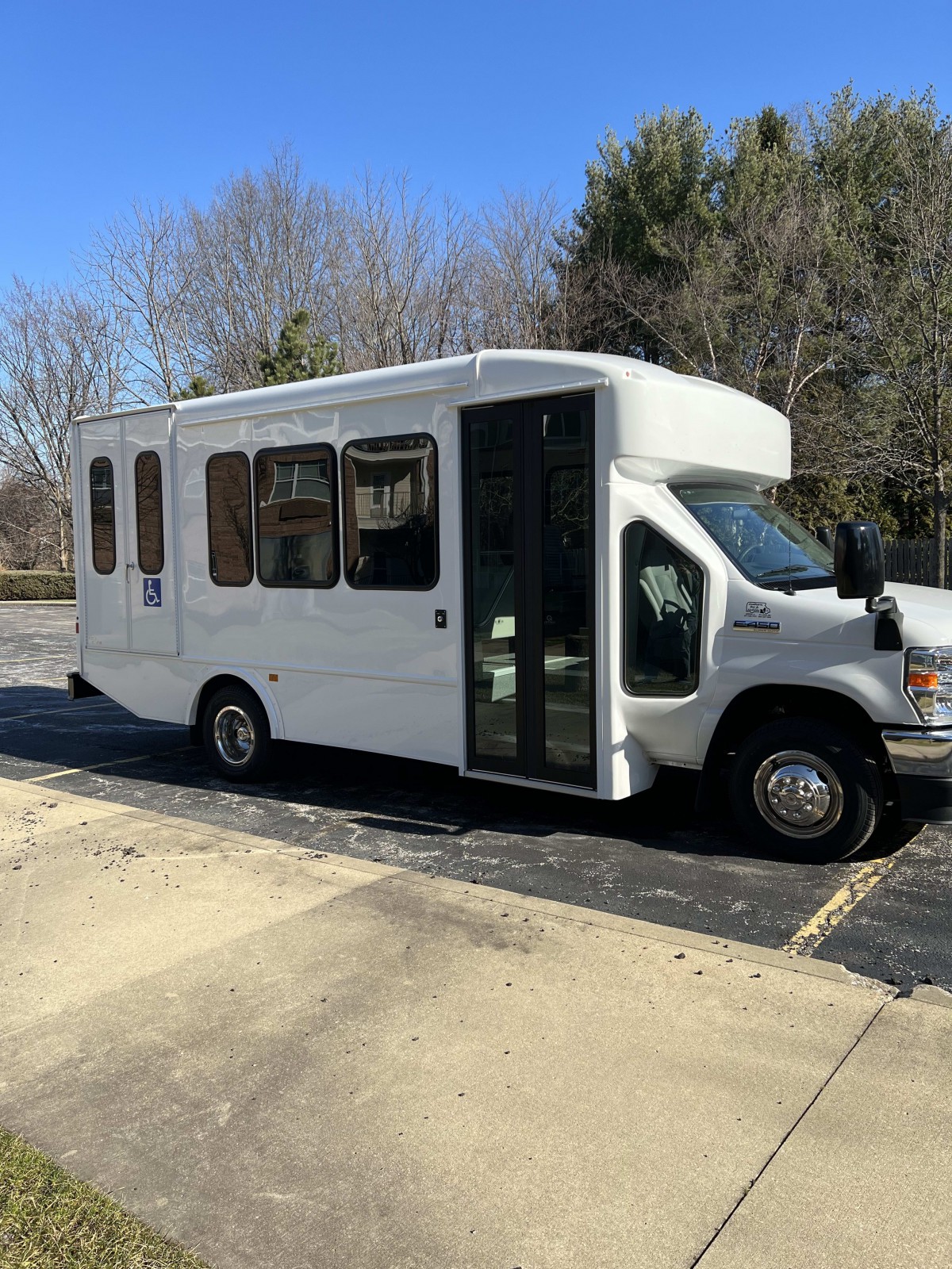 A white bus parked in a sunny outdoor parking lot.