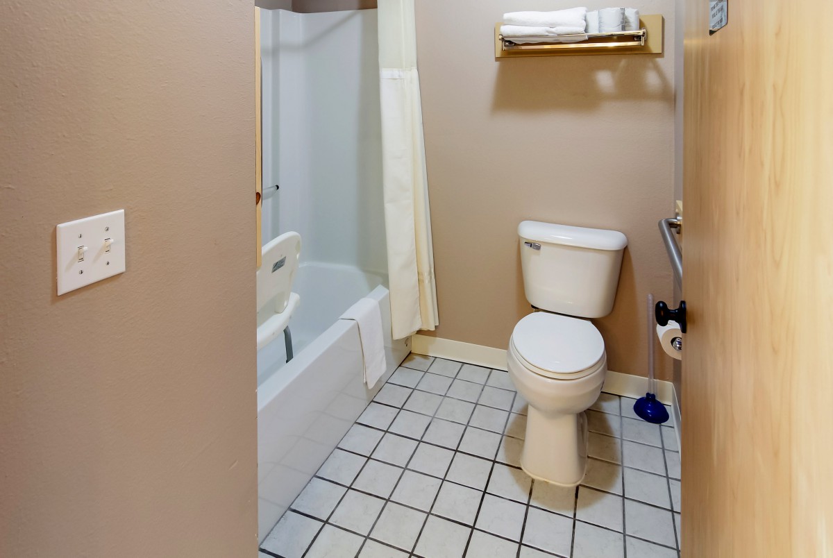 A clean and functional bathroom with a toilet, bathtub, tiled floor, and towel rack.