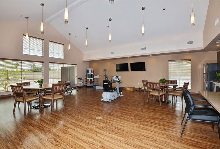 A spacious and modern dining area with hardwood floors, ample seating, large windows, and ceiling lights.