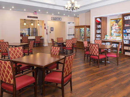 An elegantly designed dining area with red cushioned chairs and wooden tables, featuring a chandelier and decorative elements.