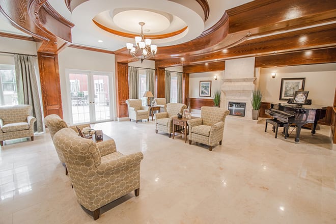 A spacious and elegantly designed living room with a cozy seating area, fireplace, and chandelier.