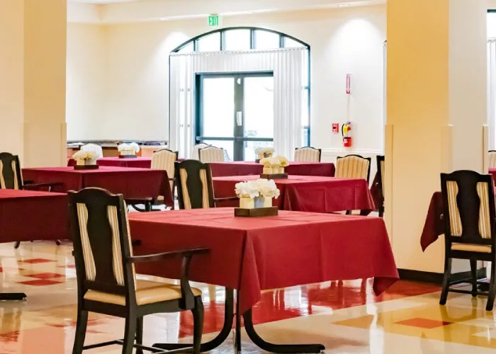 An empty restaurant dining area with tables and red tablecloths.