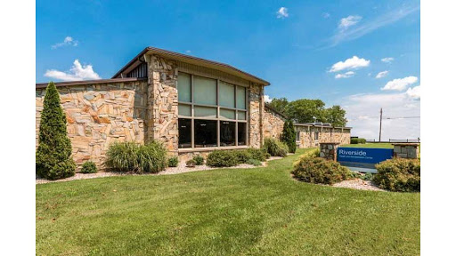 A beautifully designed stone building surrounded by well-maintained grass and a clear blue sky.