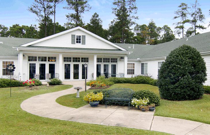 A charming house with a well-maintained garden and surrounding trees.