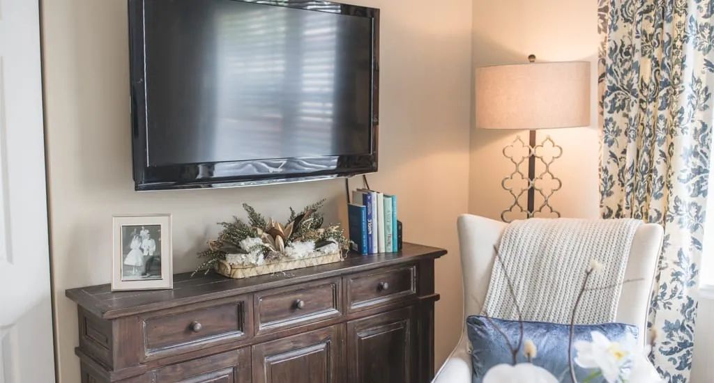 Cozy living room with a flat-screen TV, decorative cabinet, and comfortable seating.