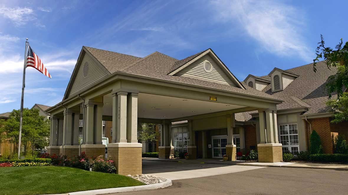 A building entrance with a covered driveway and supporting columns.