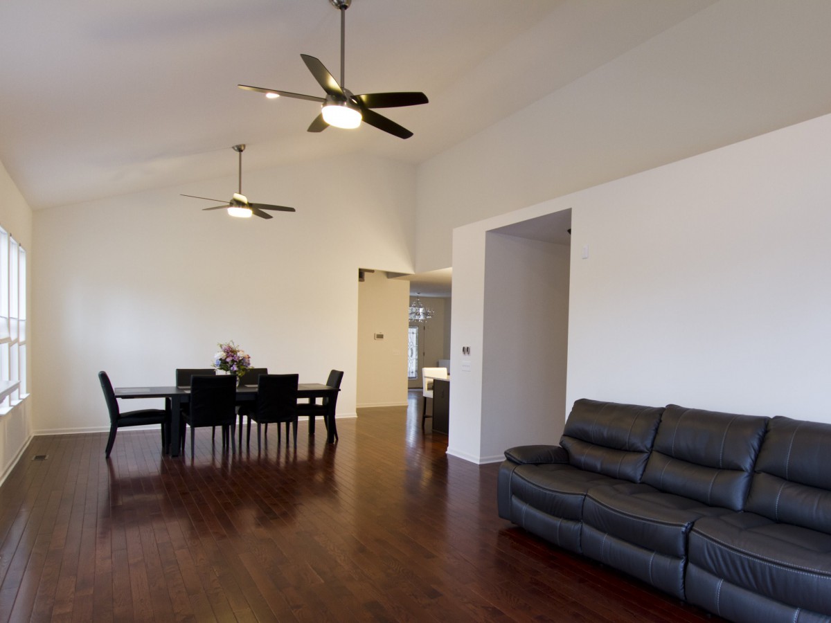 A spacious living and dining area with modern furniture and ceiling fans.