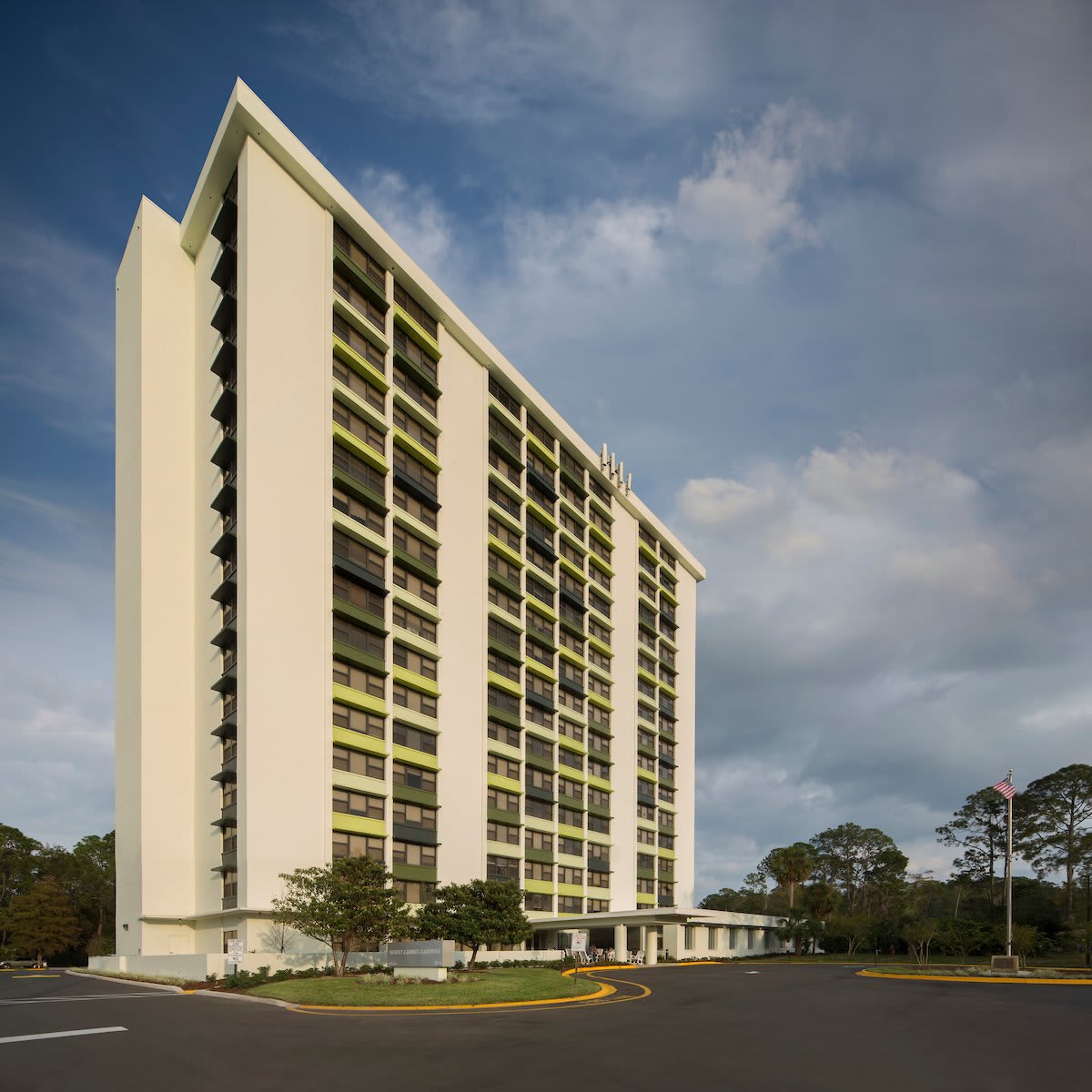A modern high-rise residential building under a partly cloudy sky.