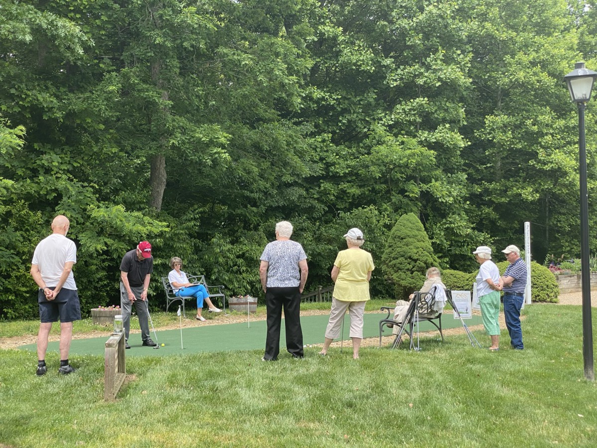 A group of seniors enjoying a day of minigolf surrounded by greenery.