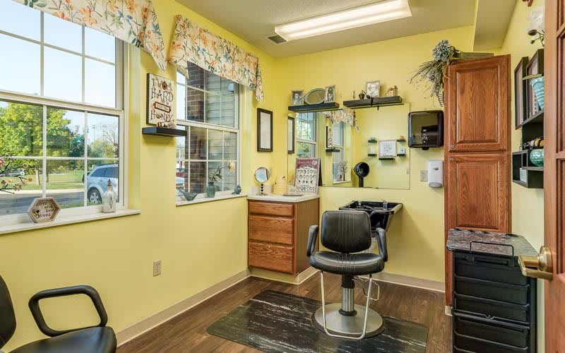 A cozy hair salon with yellow walls and a comfortable styling chair by the window.