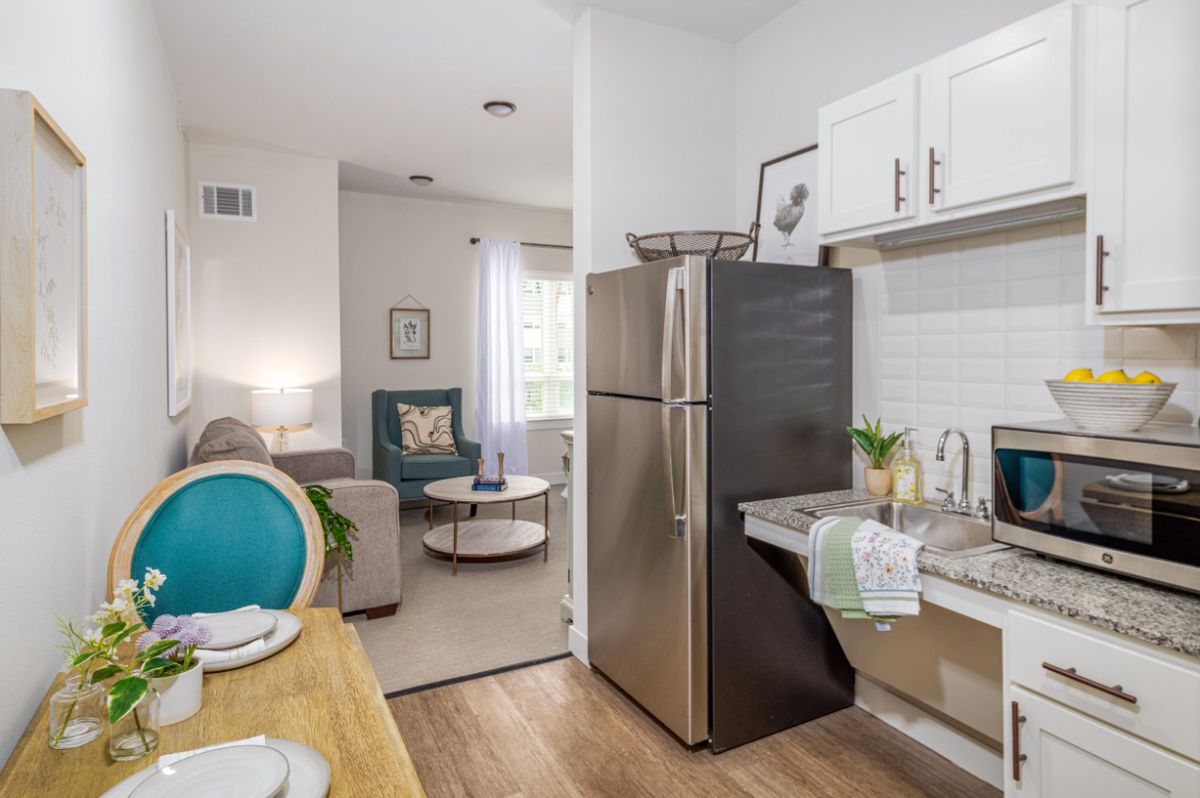 A modern open layout apartment featuring a cozy kitchen and living room with bright lighting.