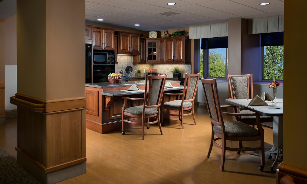 A modern kitchen and dining area featuring wood cabinets and a table with chairs.