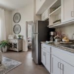 A modern kitchen interior featuring white cabinets, a stainless steel refrigerator, and tasteful decor.