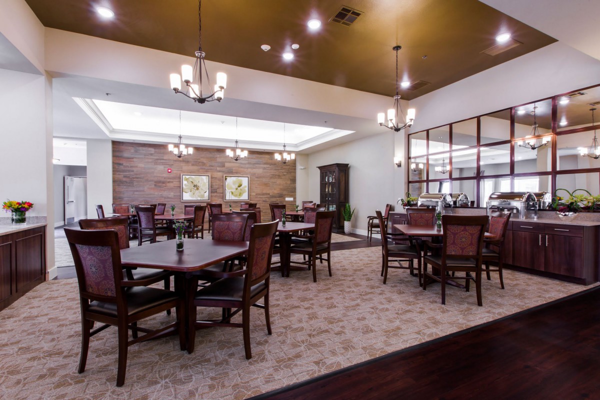 A spacious and elegantly designed dining area with multiple tables and chairs, featuring ambient lighting and tasteful decor.