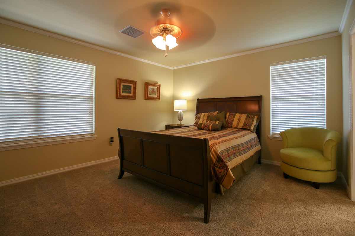 A cozy bedroom with a wooden bed, soft lighting, and comfortable seating.