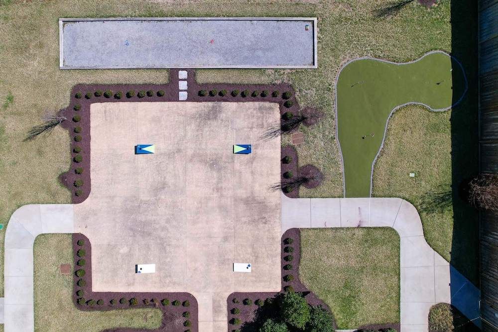 Aerial view of a parking lot with pathways and landscaped areas.